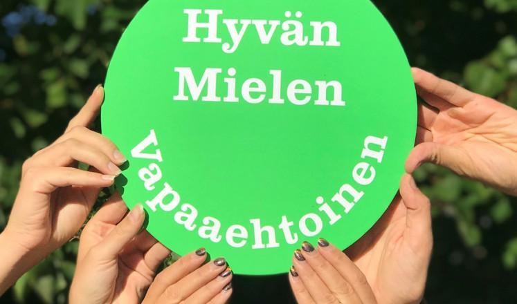 Kädet nostavat kylttiä "Hyvän MIelen Vapaaehtoinen"