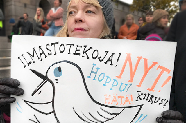 Nainen mielenosoituksessa. Kädessä kyltti, jossa teksti: Ilmastotekoja nyt. Hoppu, hätä, kiire.