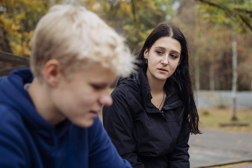 Teini-ikäiset, vakavalta vaikuttavat poika ja tyttö keskustelevat