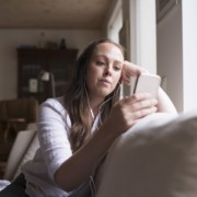 Nuori tyttö katsoo puhelinta kuulokkeet korvilla