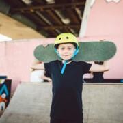ung person med hjälm på huvudet och skateboard på axeln