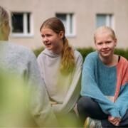 Kolme tyttöä istuskelee ulkona